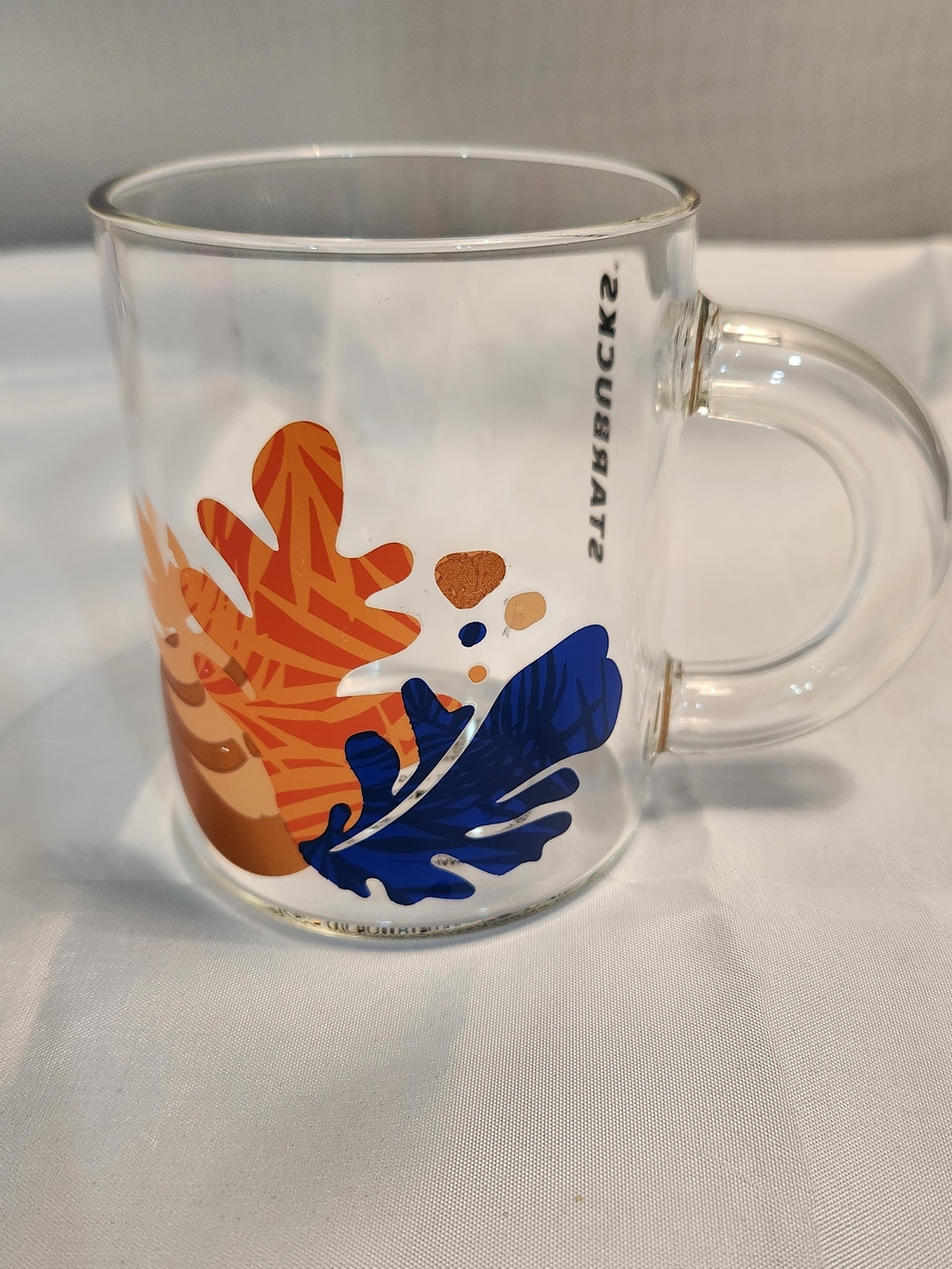 Starbucks Clear Glass Mug with Orange and Blue Leaf Design